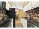 Galley kitchen featuring black appliances, white cabinets, and dining nook at 7755 E Quincy Ave # 206, Denver, CO 80237