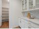 Butler's pantry featuring marble countertops, white cabinetry, and open shelving for storage and organization at 22263 Boundstone St, Parker, CO 80138