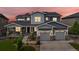 Beautiful two-story home with a manicured lawn, stone accents, and a three-car garage under a colorful dusk sky at 22263 Boundstone St, Parker, CO 80138
