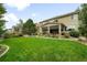 Expansive backyard featuring a lush lawn, stone patio, and meticulously maintained landscaping at 15348 W 75Th Pl, Arvada, CO 80007