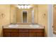 Bathroom with a double sink vanity, large mirror, and warm color palette at 15348 W 75Th Pl, Arvada, CO 80007