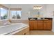 Spacious main bathroom with dual vanities, soaking tub, and a large window with a scenic view at 15348 W 75Th Pl, Arvada, CO 80007