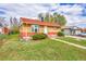Charming brick home with a red roof, mature landscaping, and a well-maintained lawn at 6990 Larsh Dr, Denver, CO 80221