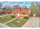 Well-manicured lawn with brick home, red roof and private driveway at 6990 Larsh Dr, Denver, CO 80221