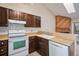 Traditional kitchen with wood cabinets, white appliances, and a double bowl sink at 9612 W Chatfield Ave # C, Littleton, CO 80128