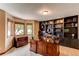 Home office boasts a large wooden desk, built-in shelving, and natural light from windows at 8682 N Sundown Trl, Parker, CO 80134