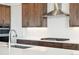 Close-up of kitchen boasts a range hood, stove, faucet, and stainless steel appliances at 6653 Bridlespur St, Castle Pines, CO 80108