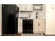 Compact kitchenette features sleek black appliances, neutral cabinets, and stylish tile backsplash at 17870 New London Rd, Monument, CO 80132