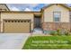 Tan house with stone accents, two-car garage, and landscaped lawn at 9804 Truckee St, Commerce City, CO 80022