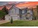 Charming two-story home with a three-car garage, well-manicured lawn, and inviting front porch at sunset at 20113 Edinborough Ct, Parker, CO 80138