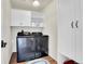 Well-lit laundry room featuring a black Samsung washer and dryer set and white cabinets at 1628 Taos St, Brighton, CO 80603