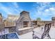 A charming patio with a stone fireplace, wood storage, comfortable seating, and blue accent rug at 1628 Taos St, Brighton, CO 80603
