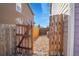 Narrow fenced side yard featuring decorative gravel and a wooden access gate for utility access or storage at 1628 Taos St, Brighton, CO 80603