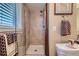 Bathroom featuring a glass-enclosed shower with beige tile, a shower caddy, and brushed-nickel hardware at 164 W Acoma Dr, Littleton, CO 80120