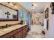 Bathroom featuring a granite vanity, marble tile floors and shower surround, and bronze fixtures at 164 W Acoma Dr, Littleton, CO 80120