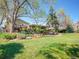 Spacious landscaped yard showcasing a stone patio, lush lawn, mature trees, and charming outdoor entertaining space at 164 W Acoma Dr, Littleton, CO 80120