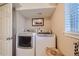 Well-lit laundry room featuring a modern washer and dryer, and white door at 164 W Acoma Dr, Littleton, CO 80120