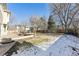 Spacious backyard with a wooden deck, patio, and lawn, partially covered in snow at 1642 S Trenton St, Denver, CO 80231