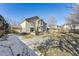 Large, fenced backyard with a wooden deck, mature trees, and a mix of grass and snow at 1642 S Trenton St, Denver, CO 80231