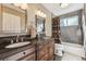 Bathroom featuring double sinks, wooden cabinetry, and a shower over tub with decorative shower curtain at 1642 S Trenton St, Denver, CO 80231