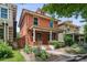 Charming brick two-story home with a covered porch, landscaped yard, flowerbeds, and decorative plants at 1007 N Ogden St, Denver, CO 80218