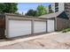 A detached two car garage with white doors and grey trim on a paved surface located in an urban environment at 1007 N Ogden St, Denver, CO 80218