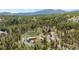 Overhead shot of a home set within a picturesque forest with surrounding neighborhood in the distance at 8600 S Warhawk Rd, Conifer, CO 80433