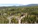 Panoramic aerial shot of a house nestled in a dense forest with mountains in the background at 8600 S Warhawk Rd, Conifer, CO 80433