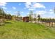 Expansive backyard featuring a grassy lawn, wooden home, and mature trees at 8600 S Warhawk Rd, Conifer, CO 80433