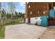 View of the home's back exterior with a door leading to the partially finished basement and concrete area at 8600 S Warhawk Rd, Conifer, CO 80433