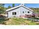 Backyard view of home featuring a wooden deck, patio table, and surrounding natural landscape at 11348 Ranch Elsie Rd, Golden, CO 80403