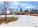 Large backyard with snowy lawn and mature trees at 8010 W Chestnut Dr, Littleton, CO 80128