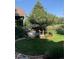 Backyard with a lush green lawn, a mature tree, and a stone patio perfect for outdoor entertaining at 27 Buckthorn Dr, Littleton, CO 80127