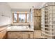 Bright bathroom with a soaking tub and shower featuring glass blocks, offering both style and natural light at 27 Buckthorn Dr, Littleton, CO 80127