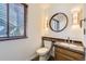 Cozy bathroom with granite countertop, round mirror, wood blinds, and decorative sconces at 27 Buckthorn Dr, Littleton, CO 80127