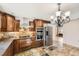 Modern kitchen featuring stainless steel appliances, granite countertops, wood cabinets, and stone tile flooring at 27 Buckthorn Dr, Littleton, CO 80127