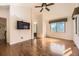 Hardwood main bedroom with modern ceiling fan and window, bathed in natural sunlight, with a TV at 27 Buckthorn Dr, Littleton, CO 80127