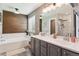 Bright bathroom featuring double sinks, soaking tub, and wood accent wall at 16662 W 61St Pl, Arvada, CO 80403