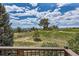 Scenic backyard view from the deck, overlooking a lush green hillside with scattered trees and a cloudy sky above at 7083 Turweston Ln, Castle Pines, CO 80108