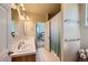 Bathroom featuring double sinks, decorative mirrors, and a shower with glass door at 7083 Turweston Ln, Castle Pines, CO 80108