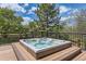 Outdoor hot tub on a wooden deck with a metal railing and trees in the background on a sunny day at 7083 Turweston Ln, Castle Pines, CO 80108