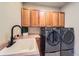 Laundry room features modern washer and dryer units, a sink and wood cabinets at 7083 Turweston Ln, Castle Pines, CO 80108