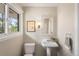 Charming powder room features pedestal sink, decorative mirror, and bright window at 2907 Hiwan Dr, Evergreen, CO 80439