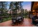Outdoor dining area on a wooden deck, offering scenic views of the surrounding trees at sunset at 2907 Hiwan Dr, Evergreen, CO 80439