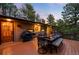 Well-lit outdoor dining area on a wooden deck, perfect for evening gatherings surrounded by trees at 2907 Hiwan Dr, Evergreen, CO 80439