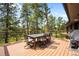 Outdoor dining area on a wooden deck with a view of lush trees and a blue sky at 2907 Hiwan Dr, Evergreen, CO 80439