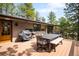 Spacious wooden deck featuring an outdoor dining set and grilling area, surrounded by lush trees and natural light at 2907 Hiwan Dr, Evergreen, CO 80439