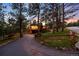 Two-story home with upper deck illuminated at dusk, surrounded by lush trees and a long driveway at 2907 Hiwan Dr, Evergreen, CO 80439