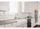 Close-up of a kitchen featuring white cabinets, subway tile backsplash, and a farmhouse sink at 2540 S Monroe St, Denver, CO 80210