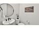 Stylish powder room features a modern, round mirror, floating sink, and decorative artwork at 9566 Poppy Way, Arvada, CO 80007